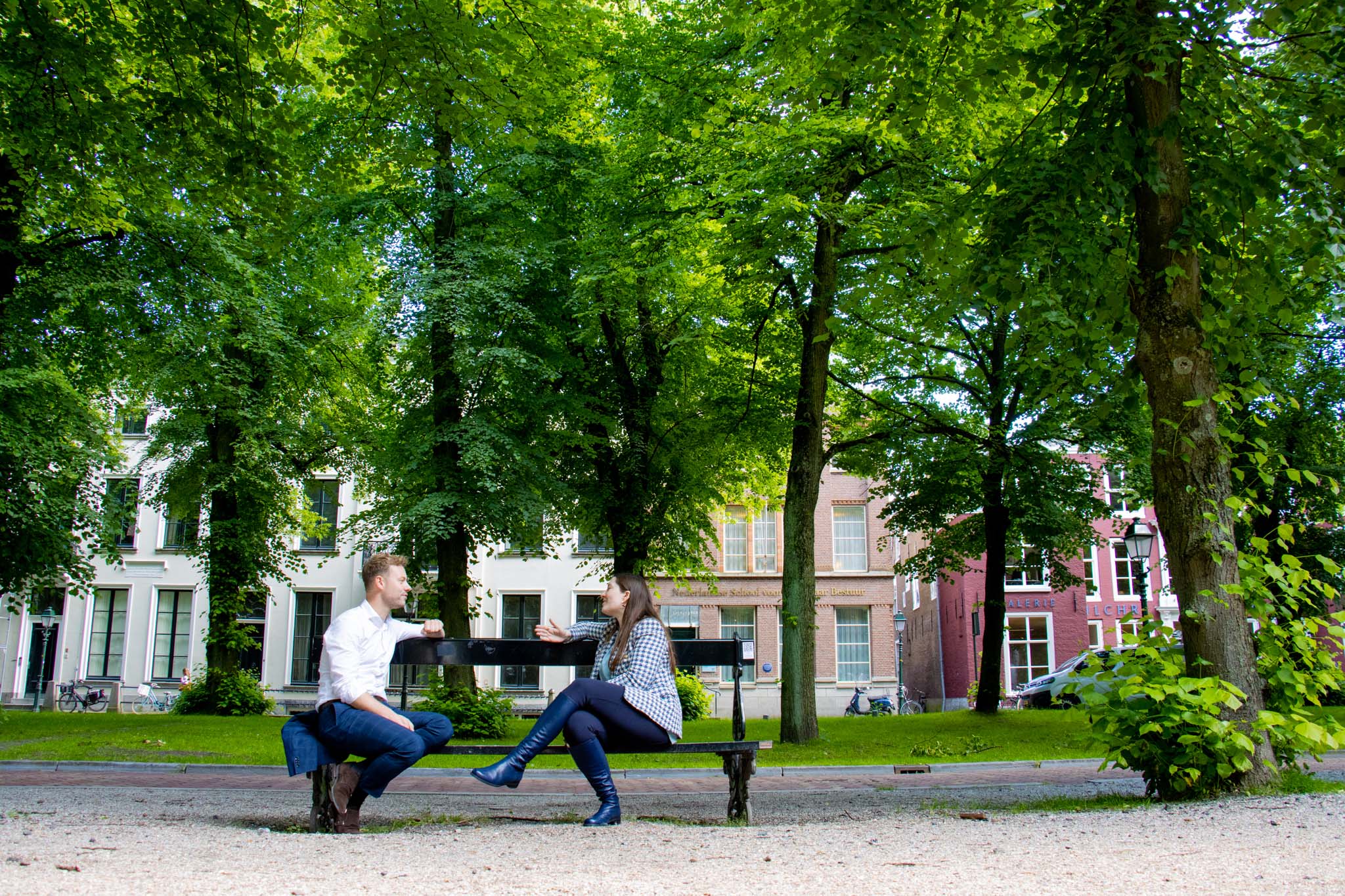Twee personen met elkaar in gesprek op parkbank voor het NSOB gebouw in Den Haag